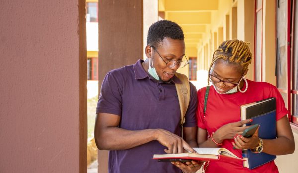 young-african-students-wearing-facemasks-holding-books-phones-campus
