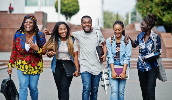 Group of five african college students spending time together on campus at university yard. Black afro friends studying. Education theme.
